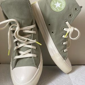 Army green converse high tops with cream laces and neon accents.